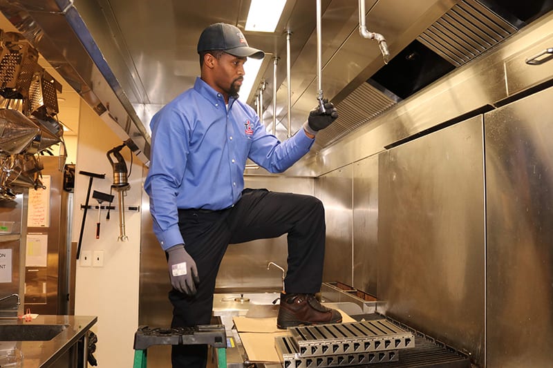 Total Fire Protection technician performing kitchen fire suppression system maintenance