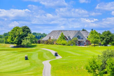 Golf place with gorgeous green and custom built luxury big house on background.