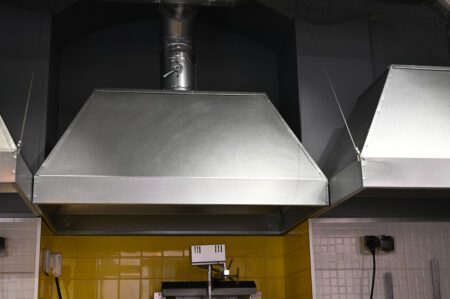 cooker hood over a stove over a stove in a restaurant.