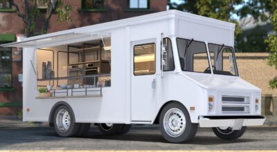 White Blank Realistic Food Truck With Detailed Cozy Interior With Warm Light On Street. Modern Cityscape. Takeaway Food And Drinks. 3d rendering. Front View