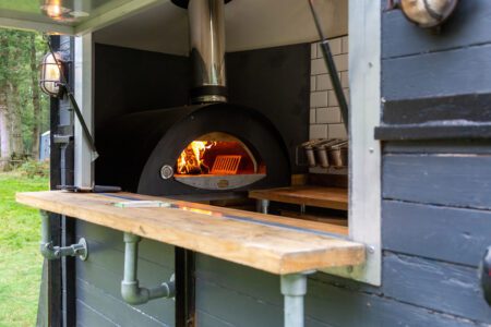 looking through a hatch of a mobile catering van with a pizza oven burning inside